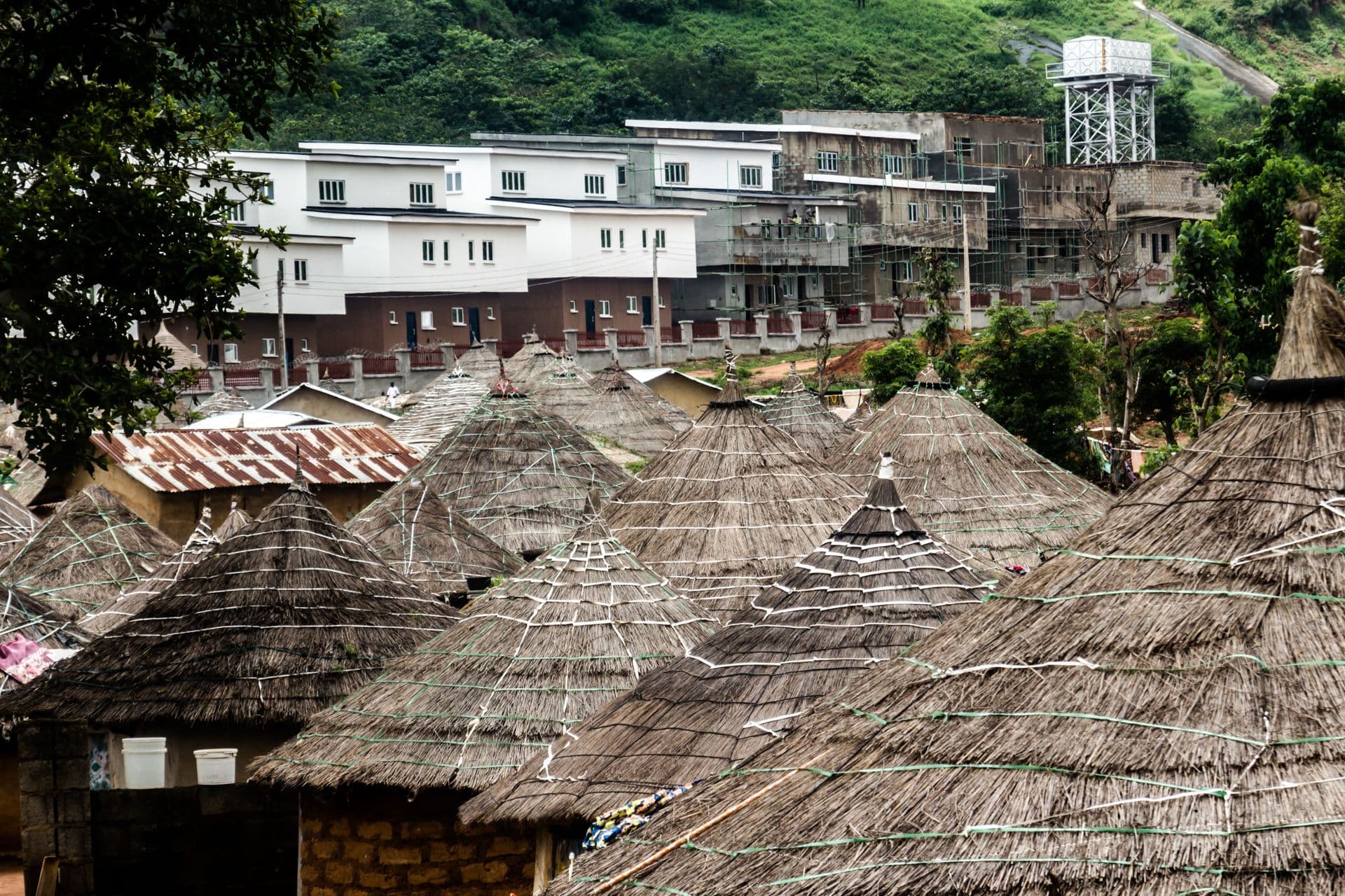 Thatched roofs in the foreground with modern buildings behind, in Abuja, Nigeria.